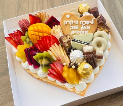 עוגת לב במבט מלמעלה, מעוצבת בחצי פירות עונתיים ובחצי שוקולדים עם הקדשה אישית
